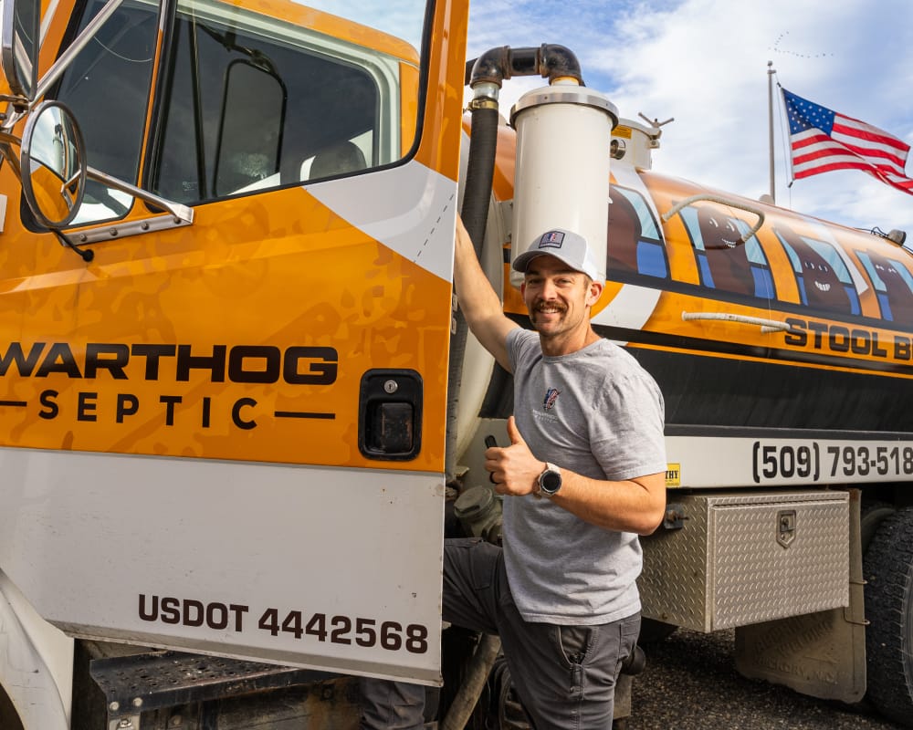Person smiling next to Warthog Septic truck.