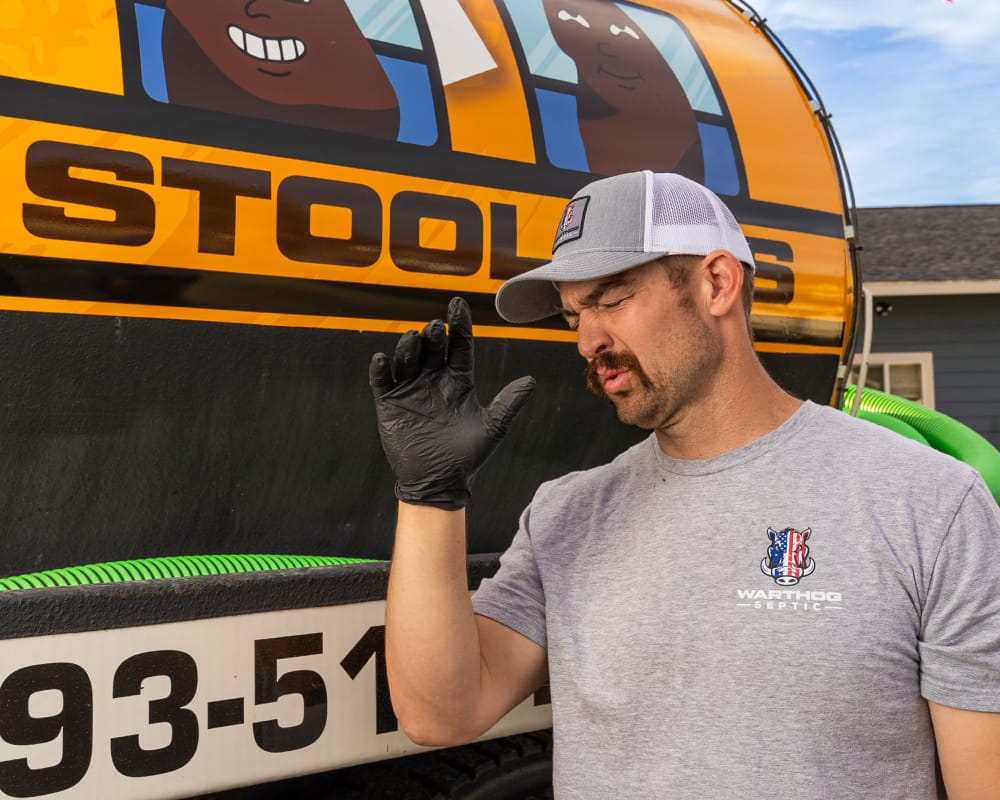 Man gesturing near septic service truck.