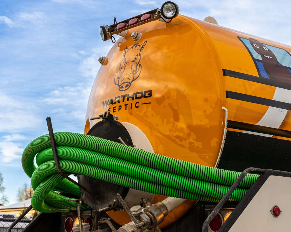Septic truck with green hoses and logo